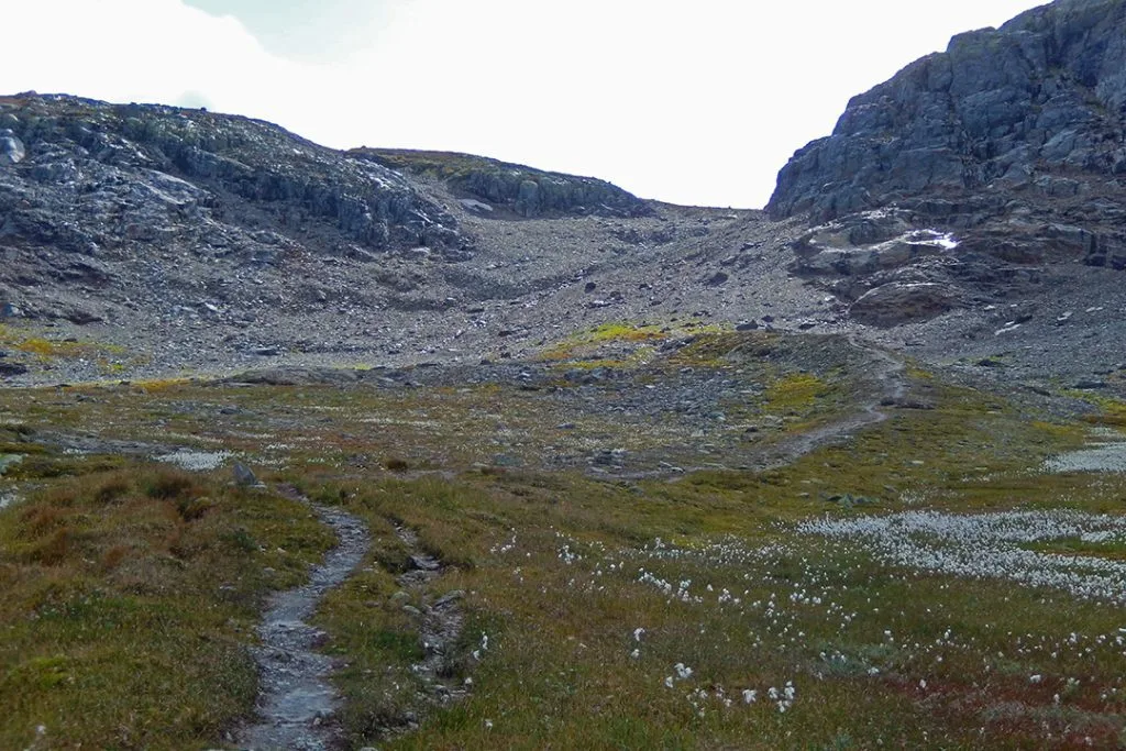Sti i bratt bakke med fjell på hver side.